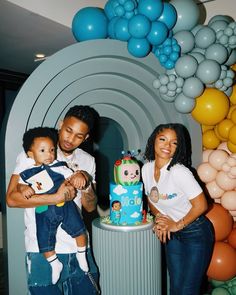 a man, woman and child standing in front of a birthday cake