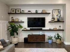 a living room filled with furniture and a flat screen tv mounted on a wall above a wooden entertainment center