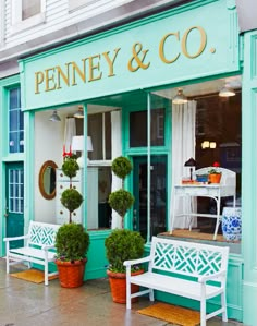 a store front with two white benches and potted plants