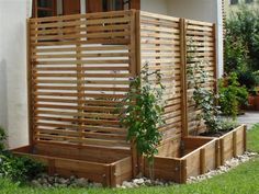 a wooden fence next to a house with potted plants on the outside and in front