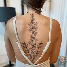 the back of a woman's neck with flowers and leaves tattooed on her upper