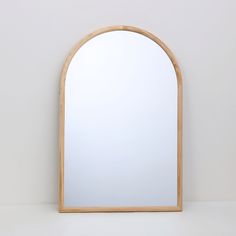 an arched wooden mirror against a white wall