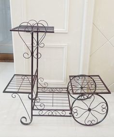 two wrought iron serving trays sitting on top of a white tile floor next to a door