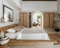 a bedroom with a bed, potted plants and pictures on the wall