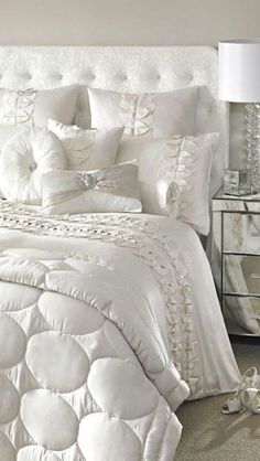 a bed with white comforters and pillows