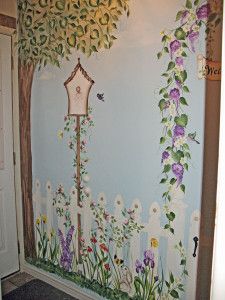 the wall is painted with flowers and vines on it, along with a birdhouse