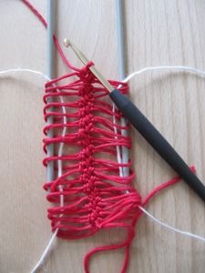 a red piece of yarn with a black crochet hook