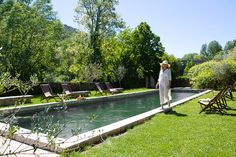 a woman standing in front of a pool surrounded by lawn chairs