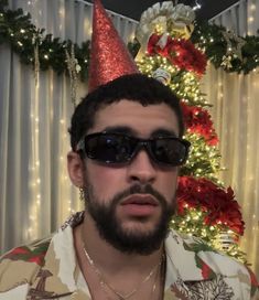 a man wearing sunglasses and a christmas tree in the background