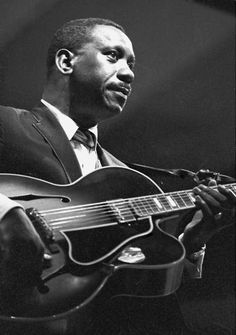 a black and white photo of a man playing an acoustic guitar