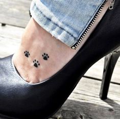 a woman's foot with a small dog paw tattoo on her left side ankle