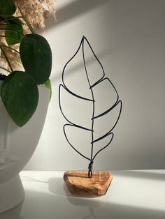 a wire sculpture sitting on top of a table next to a potted plant