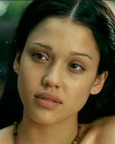 a close up of a woman wearing a necklace and looking at the camera with an intense look on her face