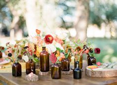 there are many bottles on the table with flowers in them