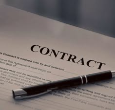 a pen sitting on top of a paper with the word contract written in it's center