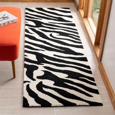 a black and white zebra print rug next to an orange chair