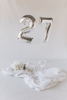 the number twenty five balloons are next to some white flowers on a cloth covered table