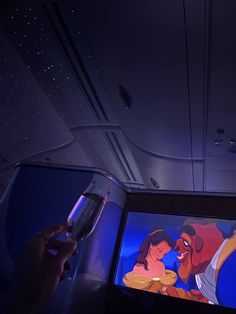 someone is holding a wine glass in front of a cartoon on the screen inside an airplane