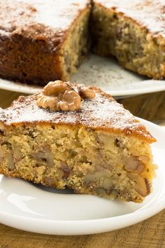 there is a piece of cake on the plate and another slice has walnuts on it