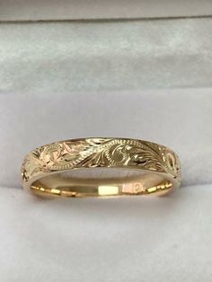 a yellow gold wedding band that has been engraved with leaves and flowers on the side