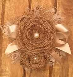 a close up of a wreath on a wooden surface with pearls and lace around it