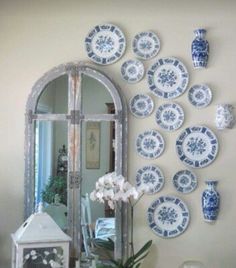 a table topped with plates and vases next to a mirror