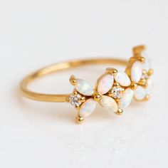 This floral ring has major fairy energy, featuring magical opal blooms punctuated by sparkling CZs set into yellow gold. This piece is a Local Eclectic exclusive! Opal 4 x 2 mm Cubic zirconia 2 mm 18k yellow gold vermeil plated Sterling silver base Band width 1.2 mm Fairy Energy, Minimalist Rings Simple, Opal Wedding Ring Set, Delicate Engagement Ring, Emerald Ring Vintage, Opal Diamond Ring, Local Eclectic, Opal Wedding, Opal Wedding Rings