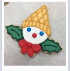 a decorated christmas cookie with holly leaves and a clown face on it's side