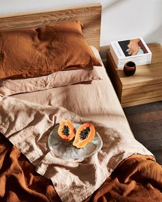 a plate with two pieces of fruit on it sitting on a bed next to an open book