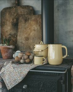 a table topped with pots and pans next to a wood stove top burner