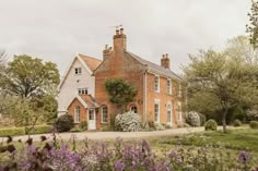 a large brick house surrounded by trees and flowers