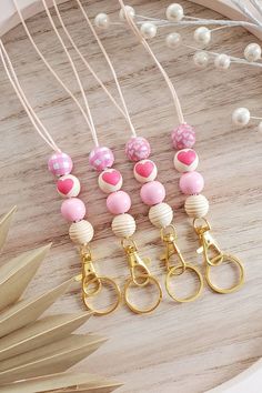 four pairs of pink and white beaded earrings with gold hooks on a wooden table