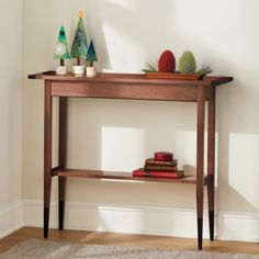 a wooden table topped with books next to a plant on top of a hard wood floor