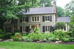 a large house surrounded by lush green trees and flowers in front of it is shown