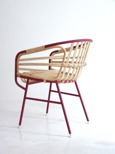 a wooden chair sitting on top of a white floor next to a red metal frame