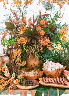 an assortment of desserts displayed on wooden trays with flowers and greenery in the background