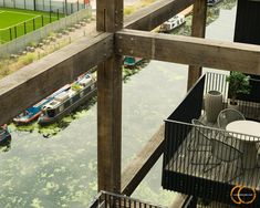 boats are docked in the water near a fenced area with benches and tables on it