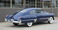 an old blue car parked in front of a building