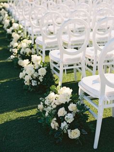 rows of white chairs lined up with flowers on the ground in front of each chair