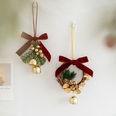 two christmas decorations hanging on the wall with bells and pinecone wreaths attached to them