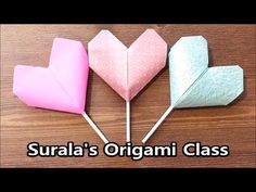 three heart shaped lollipops sitting on top of a wooden table with the words surala's origami class