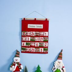 christmas calendar hanging on the wall with santa and snowman figurines next to it