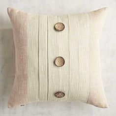 a white pillow with buttons on the front and back, sitting on a table next to a wall