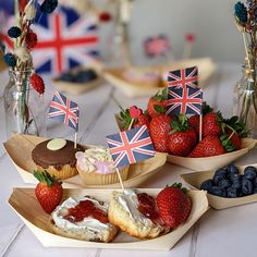 some strawberries and cupcakes with flags on them are sitting on a table