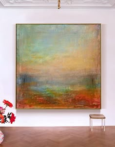 an abstract painting hangs on the wall above a chair and vase with flowers in it