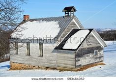 an old wooden house with snow on the roof and chimney, in front of a snowy field