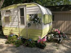 a yellow and white trailer sitting next to flowers