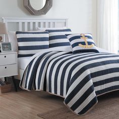 a bed with blue and white striped bedspread, pillows and an anchor pillow