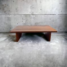 a wooden table sitting on top of a cement floor next to a white brick wall