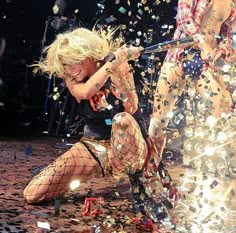 two women dressed in fishnet outfits are on stage with confetti